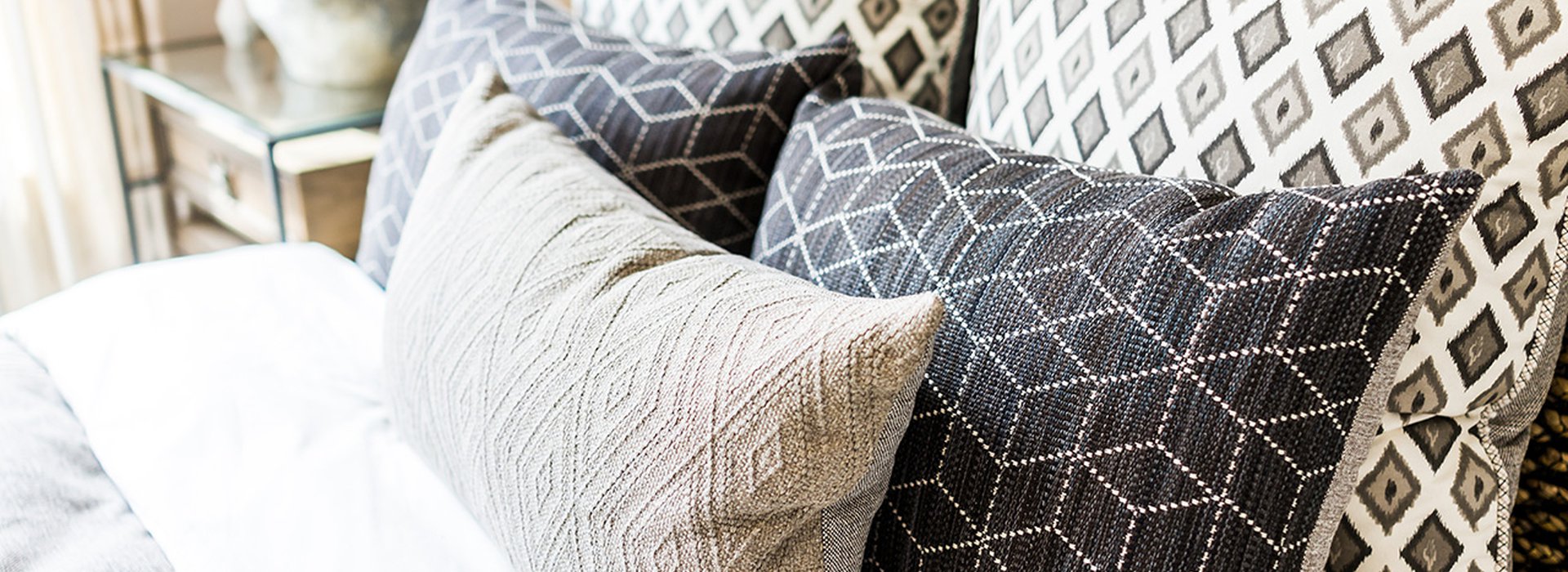 closeup-of-new-bed-comforter-with-decorative-pillows-headboard-in-bedroom-in-staging-model-home-house-or-apartment